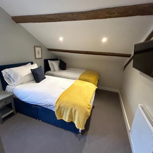 two beds in a small room with a tv at Grapes Hotel, Bar & Restaurant Snowdonia Nr Zip World in Blaenau-Ffestiniog