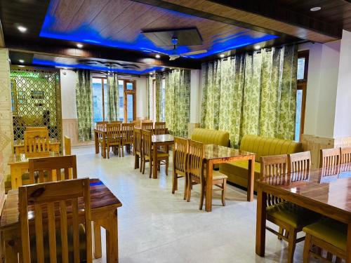 restauracja z drewnianymi stołami, krzesłami i oknami w obiekcie Nirvana -A Balcony Rooms Hotel-A True View Of Mountains w mieście Manāli