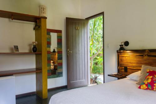 a bedroom with a bed and a sliding glass door at Pousada Aquarela in Morro de São Paulo