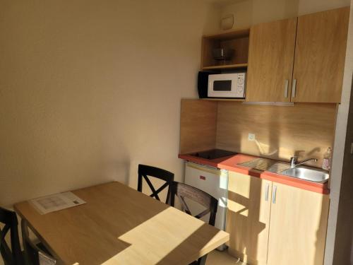 une petite cuisine avec une table et un micro-ondes dans l'établissement Le Bleu Soleil de Barcarès, au Barcarès