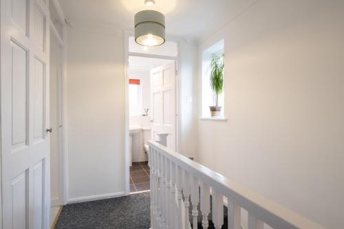 a hallway with white walls and a staircase with a potted plant at Beautiful House in South Cambridge, 14-Min Drive to the City Centre, Free Parking, No Sofabeds, Sleeps 6 in Cambridge