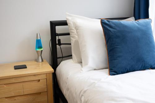 a bed with a blue pillow next to a night stand at Beautiful House in South Cambridge, 14-Min Drive to the City Centre, Free Parking, No Sofabeds, Sleeps 6 in Cambridge