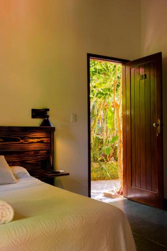a bedroom with a bed and a door to a garden at Pousada Aquarela in Morro de São Paulo