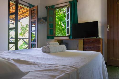 a bedroom with a white bed with a flat screen tv at Pousada Aquarela in Morro de São Paulo