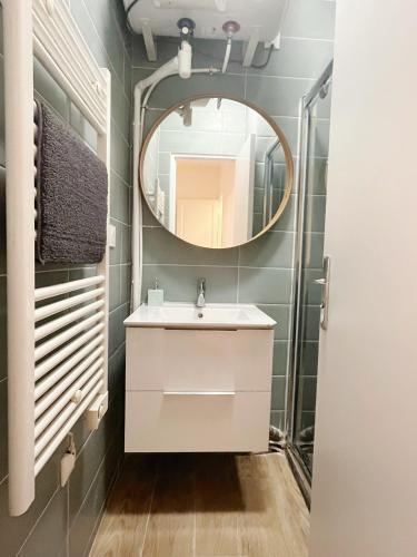 La salle de bains est pourvue d'un lavabo et d'un miroir. dans l'établissement Petite maison proche du métro, à Bagnolet
