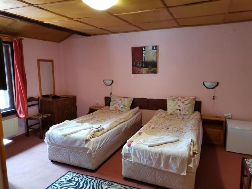 2 Betten in einem Zimmer mit rosa Wänden in der Unterkunft Family Hotel Santo Bansko in Bansko