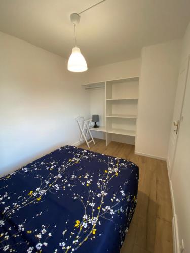 - une chambre avec une couverture bleue et des fleurs dans l'établissement Appartement Marceau Courbevoie, à Courbevoie