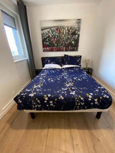 1 dormitorio con 1 cama con edredón azul en Appartement Marceau Courbevoie, en Courbevoie