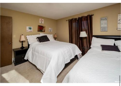 um quarto com 2 camas e lençóis brancos em Luxurious condo Moline Quad Cities 4bedrooms 2 bath em Moline