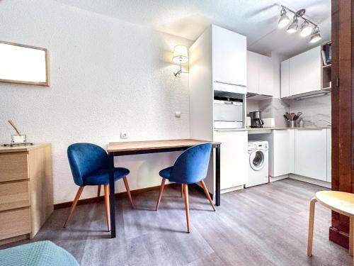 uma cozinha com uma mesa e duas cadeiras azuis em 1- Studio Brides-les-bains tout confort em Brides-les-Bains