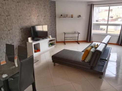 ein Wohnzimmer mit einem Sofa und einem TV in der Unterkunft Shared room in Praia in Praia
