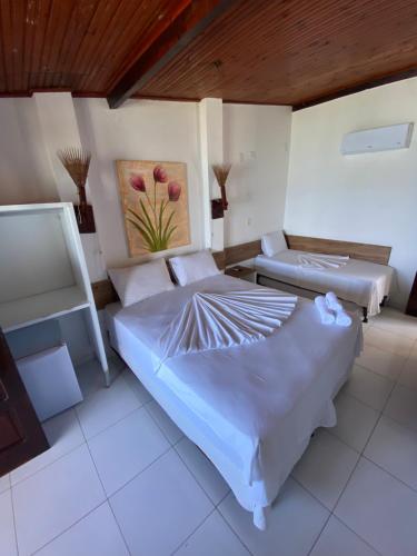 a bedroom with two beds and a painting on the wall at Pousada Maramar/terceira praia MSP in Morro de São Paulo