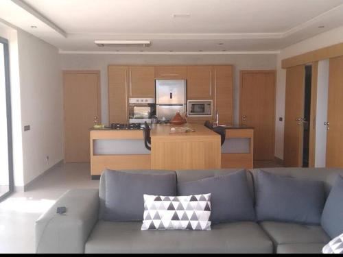 ein Wohnzimmer mit einem blauen Sofa und einer Küche in der Unterkunft HAUT de villa contemporain sur golf securise in Marrakesch