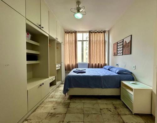 a bedroom with a blue bed and a window at Ótimo Apartamento - 500m Praia Copacabana/RJ in Rio de Janeiro