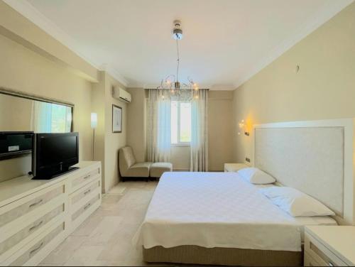 a bedroom with a large bed and a television at Gold City 5 star resort 2+1 appartement sea view and aqua park in Alanya