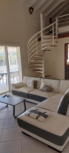 a living room with two couches and a spiral staircase at Villa Livia in Le Marin