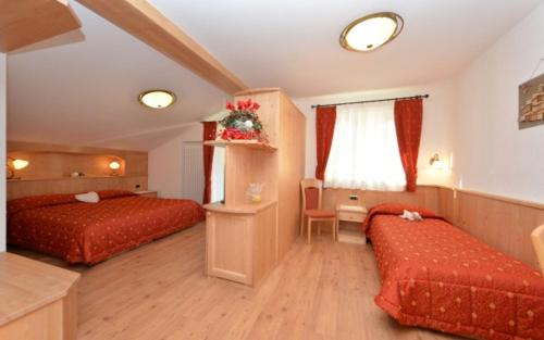 a hotel room with two beds and a window at Hotel Zirmes in Moena