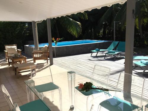 eine Terrasse mit Stühlen und einem Pool in der Unterkunft Villas Cap Est OFFRE SPECIALE PONT DE MAI 1 NUIT OFFERTE in Le François