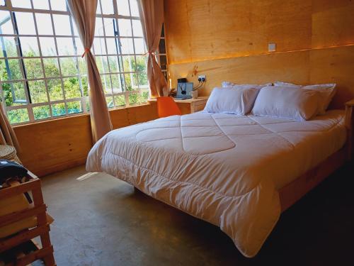 a bedroom with a large bed in a room with windows at The Cascades Cabin Nakuru in Nakuru