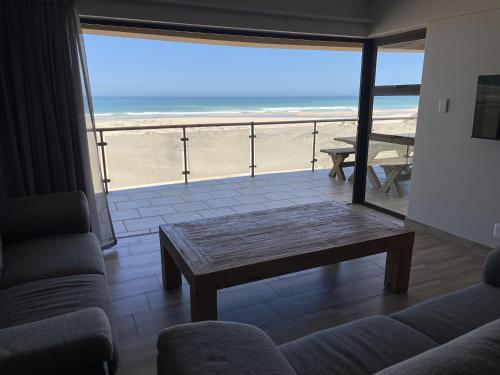 a living room with a table and a view of the beach at Paradise Beachfront Apartment in Jeffreys Bay