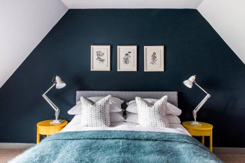 a bedroom with a blue wall with a bed and two lamps at The Loft House in Hinton Charterhouse
