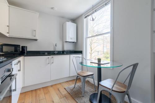 uma cozinha com mesa e cadeiras e uma janela em Fantastic Earls Court Flat em Londres