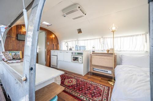a room with a bed and a kitchen in it at BeachBoys - Retro Caravan AirStream in Jeju