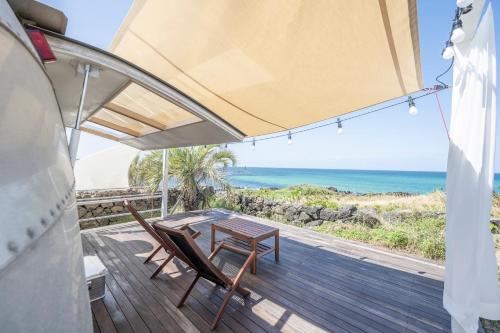 a table and chairs on a deck with a view of the ocean at BeachBoys - Retro Caravan AirStream in Jeju