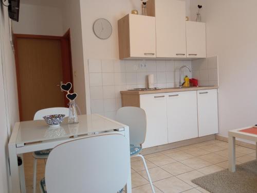 a kitchen with white cabinets and a table and chairs at Ivana in Fažana
