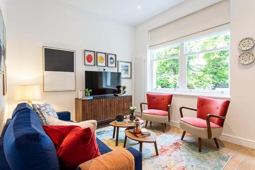 a living room with a blue couch and two chairs at Stunning Earls Court Flat in London