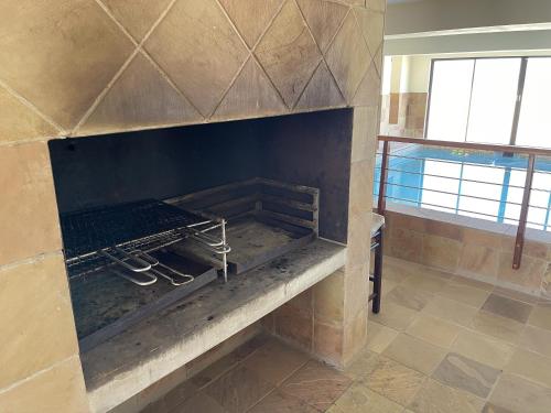 a stone fireplace in a room with a table at Paradise Beachfront Apartment in Jeffreys Bay