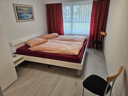 a bedroom with a bed with red curtains and a window at Haus Apollo in Saas-Almagell