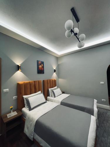 two beds in a small room with two lamps at Garden Boutique Hotel in Elbasan
