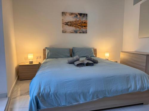 a bedroom with a large blue bed with two lamps at One in Se7en in St. Julianʼs