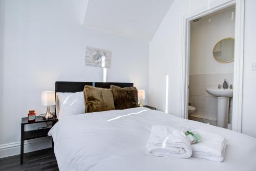 a bedroom with a white bed with towels on it at Modern 5 Bed House with Parking in Colchester