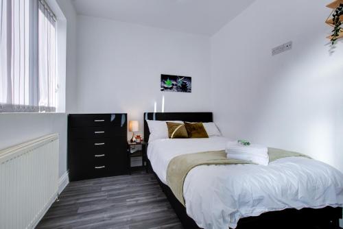 a bedroom with a bed with white sheets and gold pillows at Modern 5 Bed House with Parking in Colchester