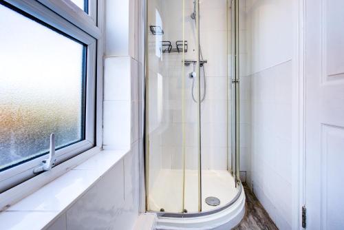 a bathroom with a shower with a toilet and a window at Modern 5 Bed House with Parking in Colchester