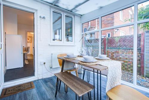 a dining room with a table and chairs and windows at Modern 5 Bed House with Parking in Colchester