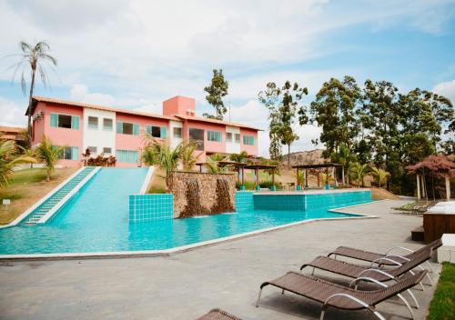 uma piscina com espreguiçadeiras em frente a um edifício em Hotel Chalé Capitólio em Capitólio