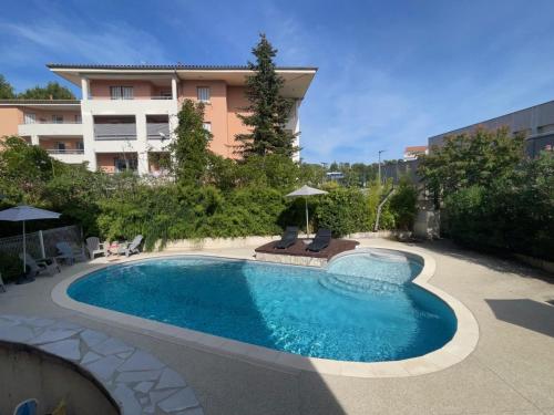 a swimming pool in front of a building at Hotel The Originals Romans-sur-Isère Le Clos des Tanneurs in Romans-sur-Isère