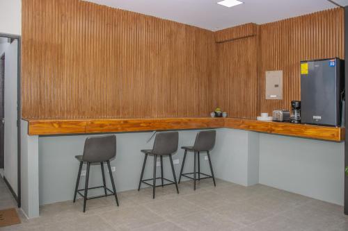 a kitchen with three bar stools and a refrigerator at The Stay San Jose in San José