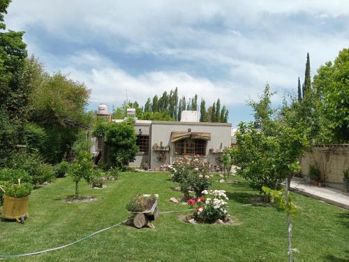 a house with a yard with flowers and trees at TRANQUILO LOFT EN VISTALBA in Vistalba