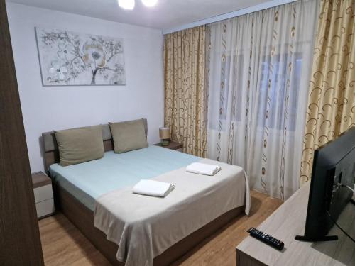 um pequeno quarto com uma cama e uma televisão em Apartament 2 camere Campulung Muscel em Cîmpulung