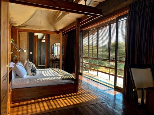 1 dormitorio con cama con dosel y ventana grande en Zulu Waters Game Reserve, en Estcourt