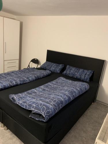 een zwart bed met blauwe kussens in een slaapkamer bij Ferienwohnung Maryna in Zwönitz