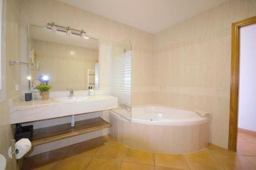 y baño con bañera, lavabo y espejo. en Villa Cunill, en Sa Torre