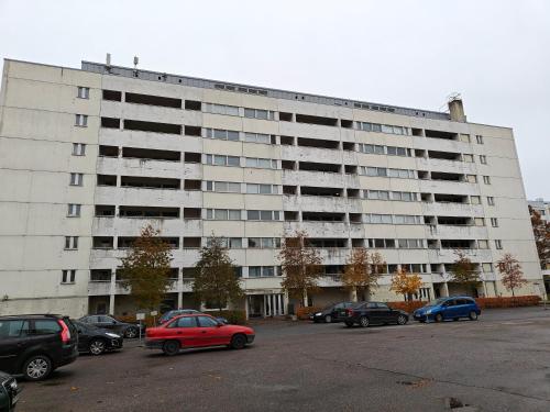 un grand bâtiment blanc avec des voitures garées dans un parking dans l'établissement Heaven Hostel, à Turku