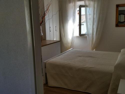 a white bedroom with a bed and a window at Holiday Home Casa Matilde in Koromačno