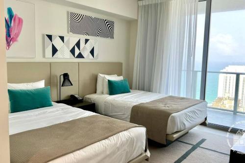 Habitación de hotel con 2 camas y ventana grande. en Luxury apartment with endless ocean views -Daily resort fee and parking not included-, en Hollywood