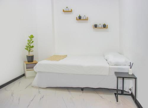 a white bedroom with a bed and a table at The Stay San Jose in San José